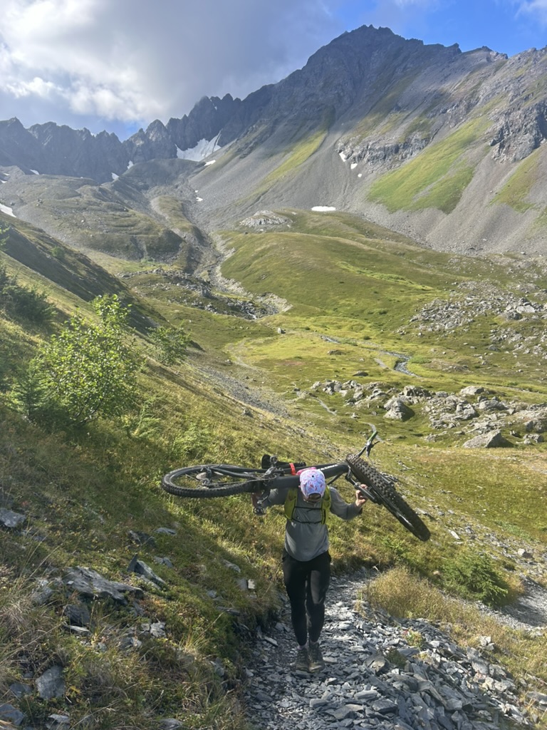 Tod carrying his bike up a rocky trail in the mountains